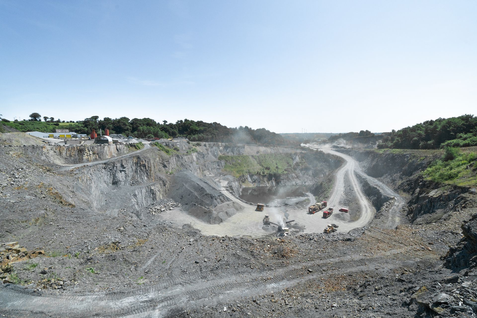 Vue d'ensemble d'une carrière avec engin de concassage et monticules de gravats.