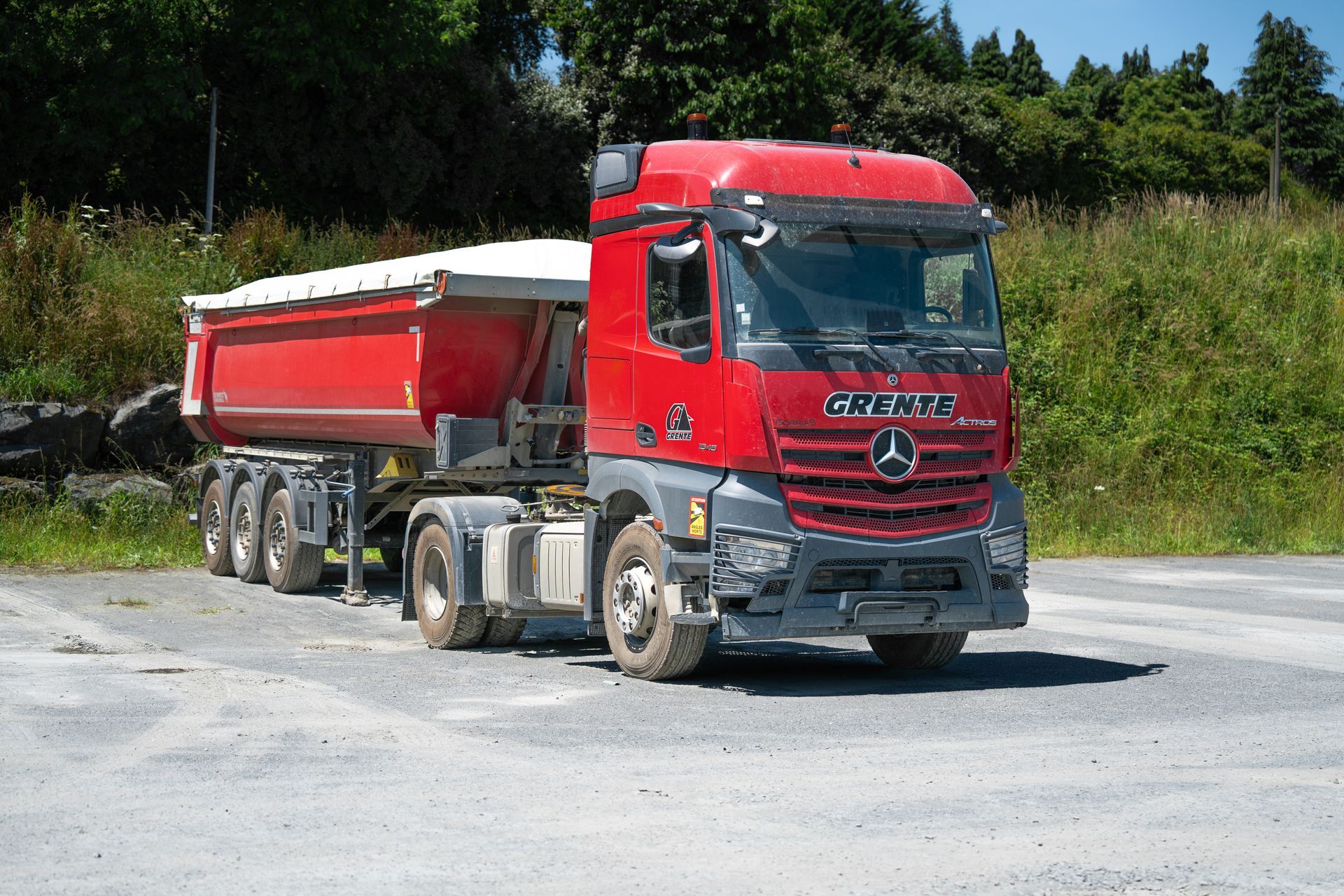 Un camion-benne rouge aux couleurs de la société Grente SAS.