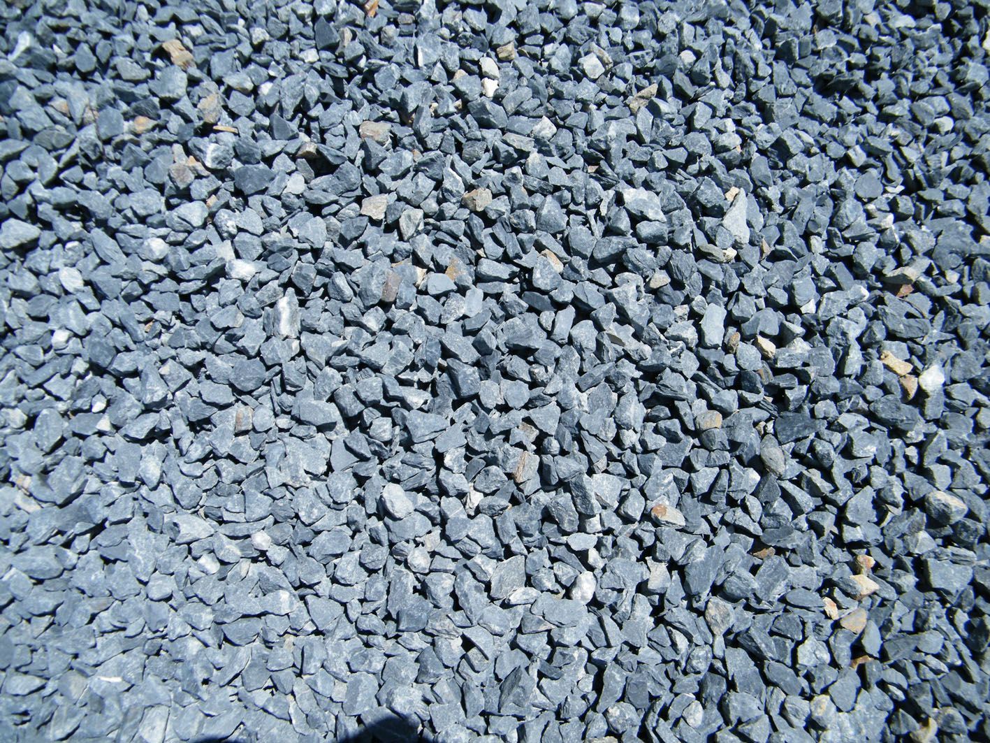 Un tas de petits cailloux ou de gravier gris anguleux, utilisés pour l'aménagement paysager ou la construction.