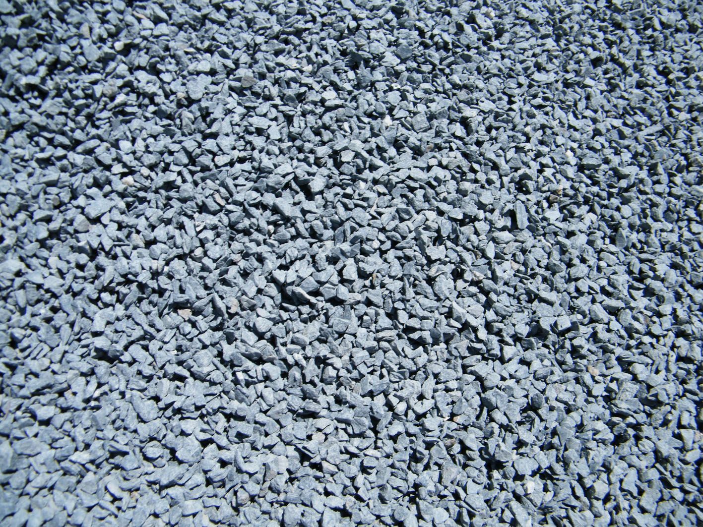 Gros plan sur un tas de petits cailloux gris, anguleux et concassés, ou de gravier.