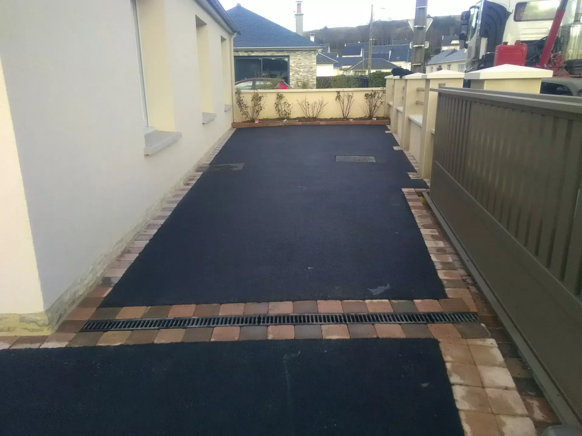 Une allée de maison goudronnée et pavée.