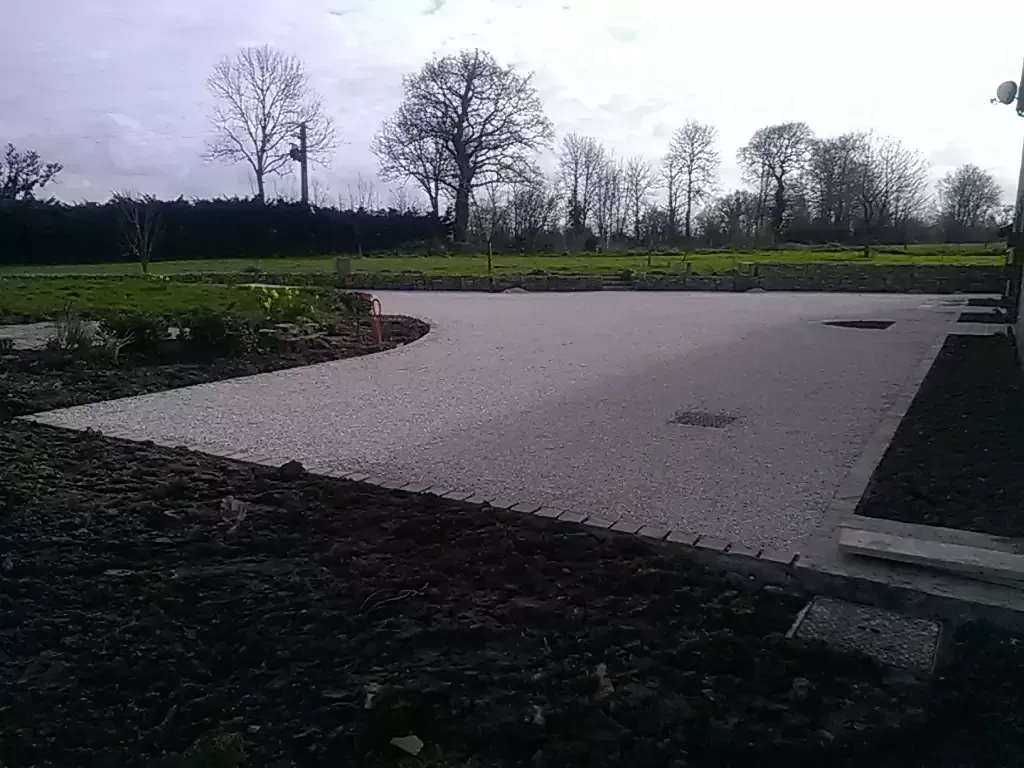Allée de gravier avec des arbres en arrière-plan sous un ciel couvert.