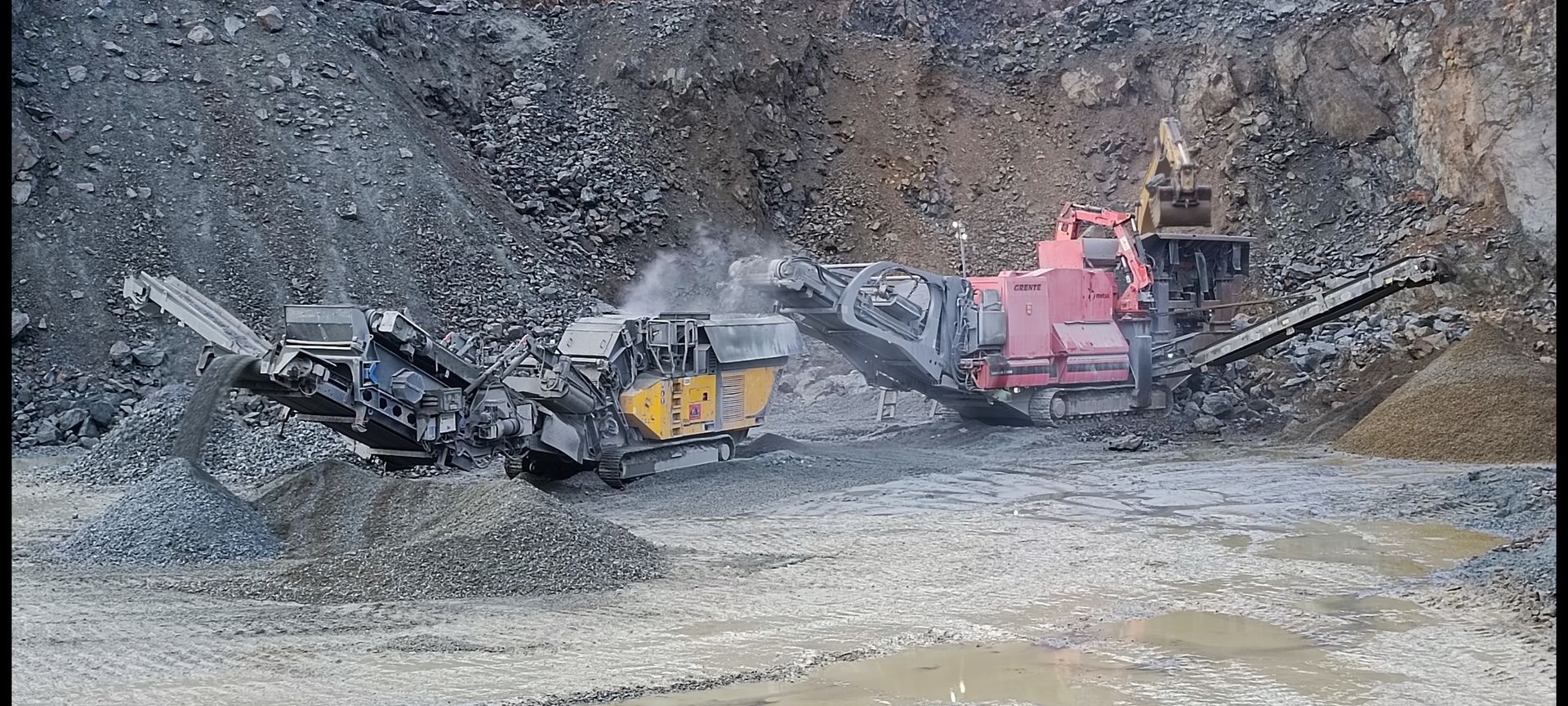Engins lourds en activité dans une carrière, traitant des roches et du gravier.