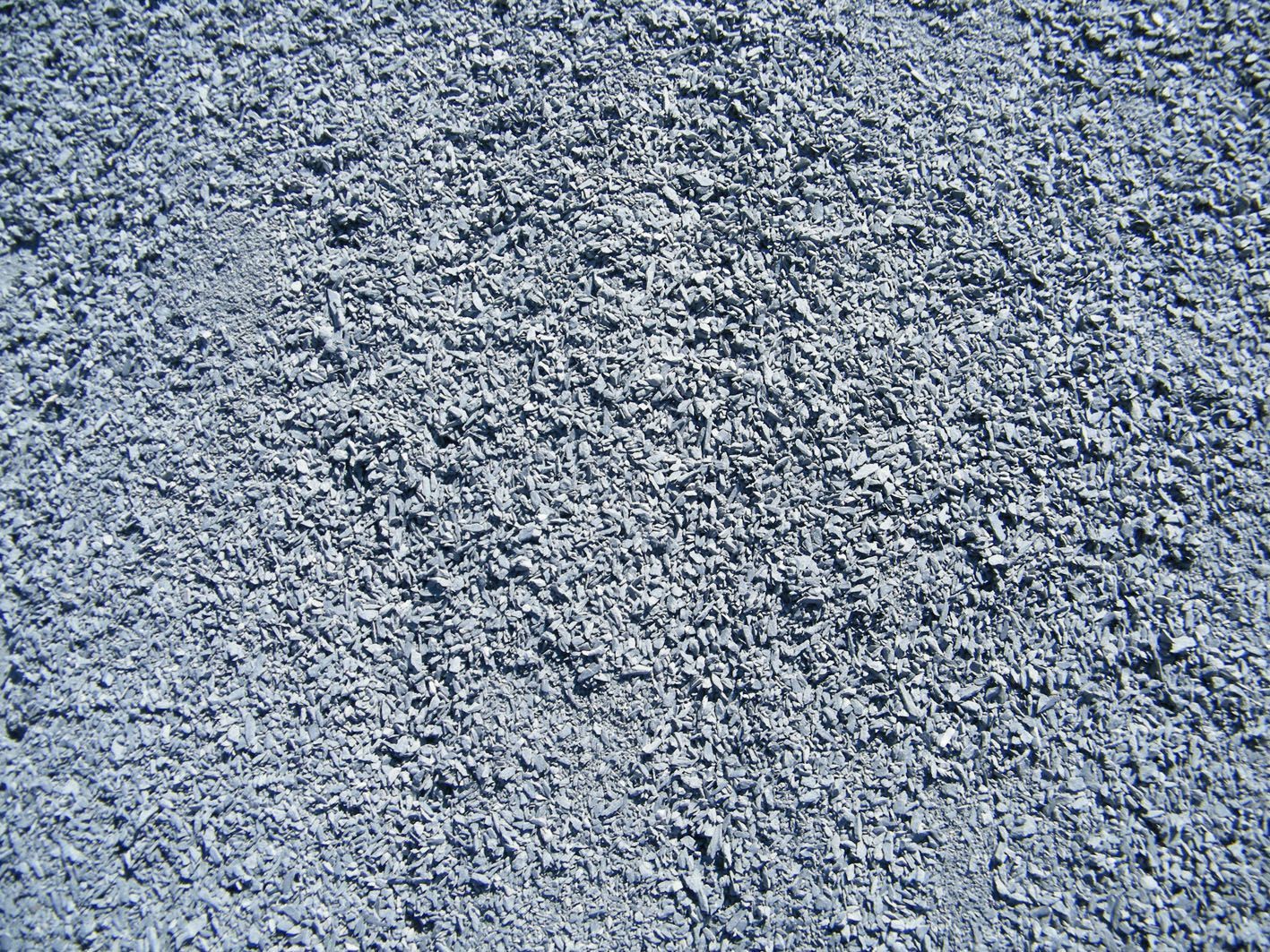 Gros plan, vue de dessus, d'une surface texturée recouverte de petites pierres grises irrégulières ou de gravier.