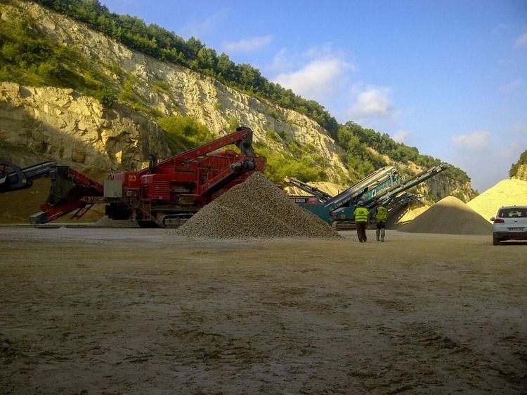 Deux personnes sur un site de carrière avec une centrale de concassage.