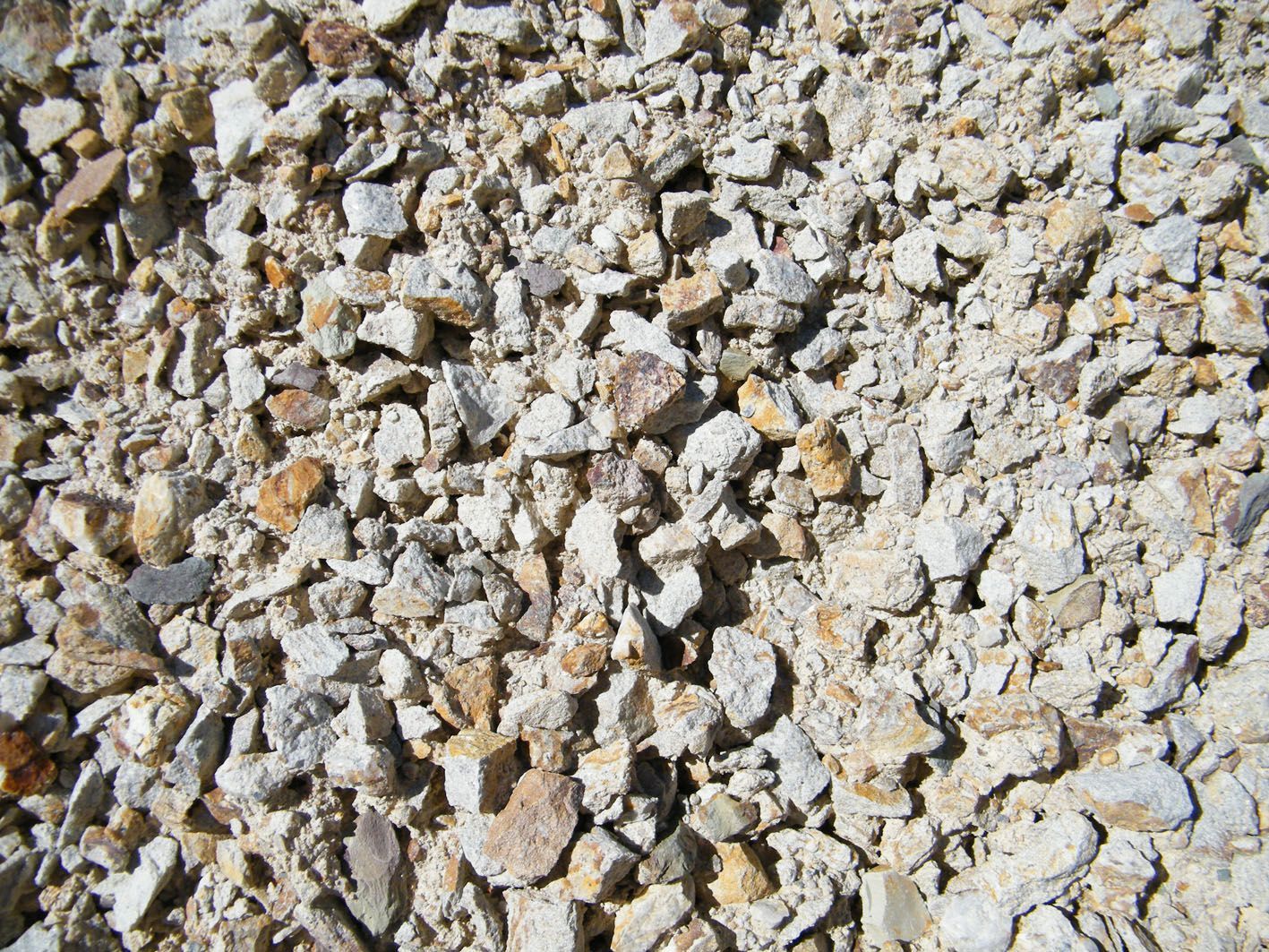Gros plan sur du gravier calcaire concassé gris clair et beige de tailles variées.