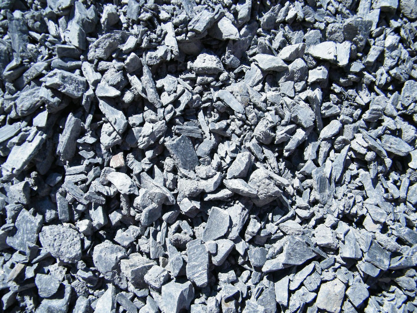 Vue de dessus de pierre ou de gravier gris concassé, montrant des formes angulaires et des textures variées.