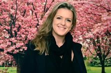 Eine Frau steht vor einem Kirschblütenbaum.