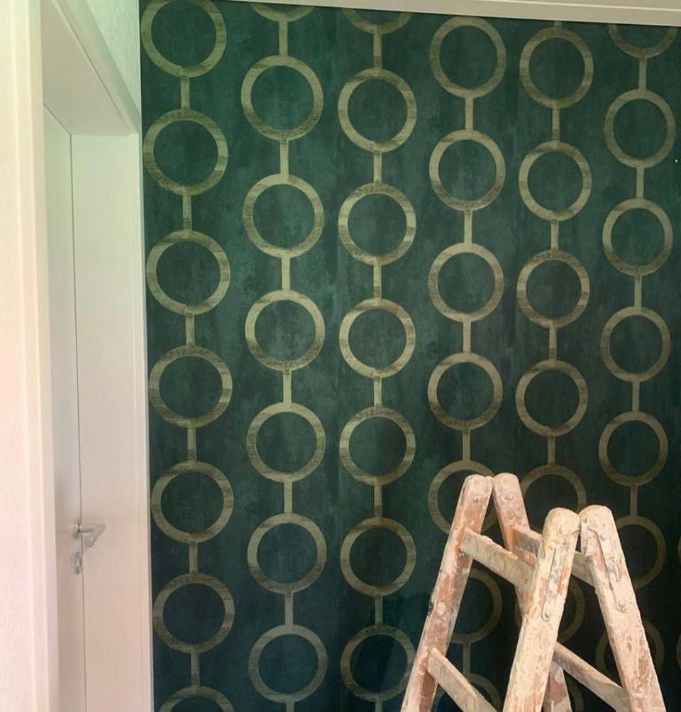 Un mur vert foncé orné d'un motif géométrique répétitif de cercles et de liens.