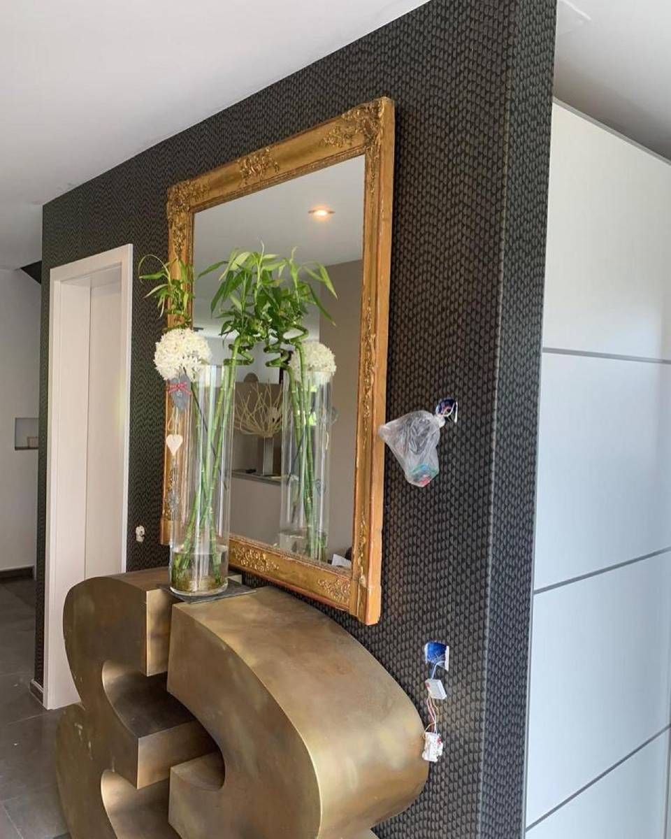 Un grand miroir à cadre doré est accroché à un mur à motifs noirs.