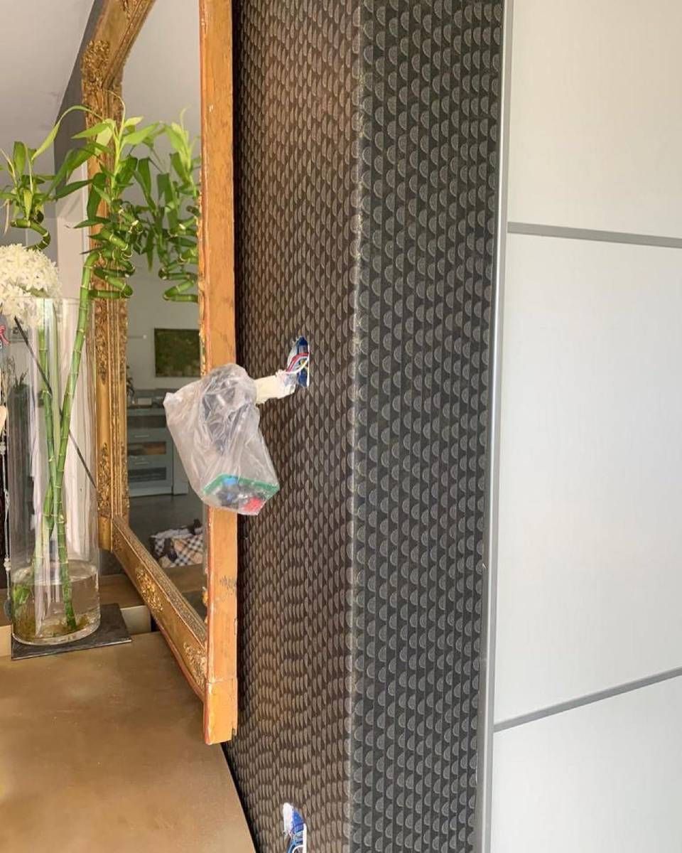 Une colonne texturée gris foncé à motifs se dresse à côté d'un grand miroir.