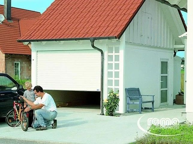 Mann und Kind mit Fahrrad in der Nähe einer weissen Garage mit offenem Rolltor.