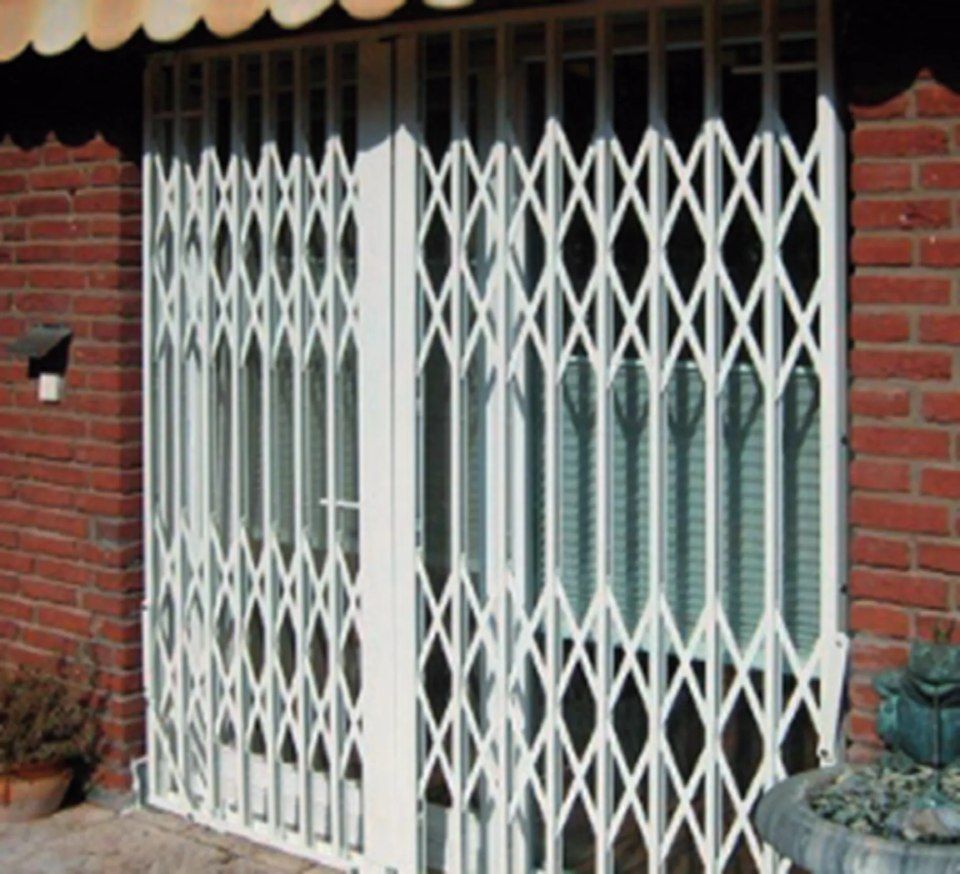 Weisses Falttor über Glastüren, eingelassen in eine Backsteinmauer.