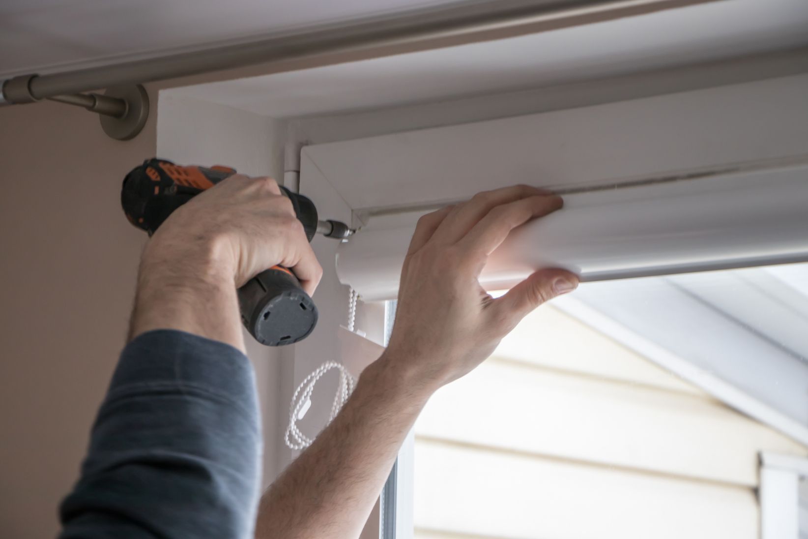 Dreieckiges Fenster mit dunklem Glas, gehalten von Konsolen, unter einem grauen Dach.