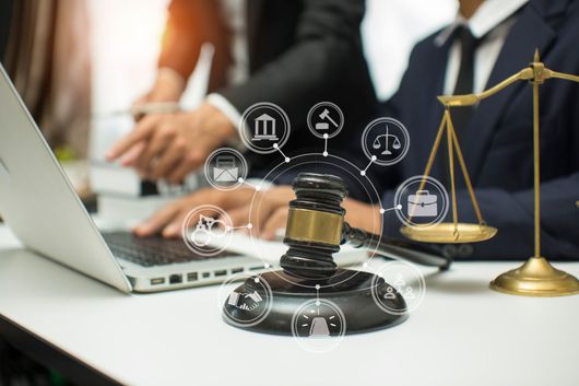 ein Mann sitzt an einem Schreibtisch mit einem Laptop und einem Hammer .