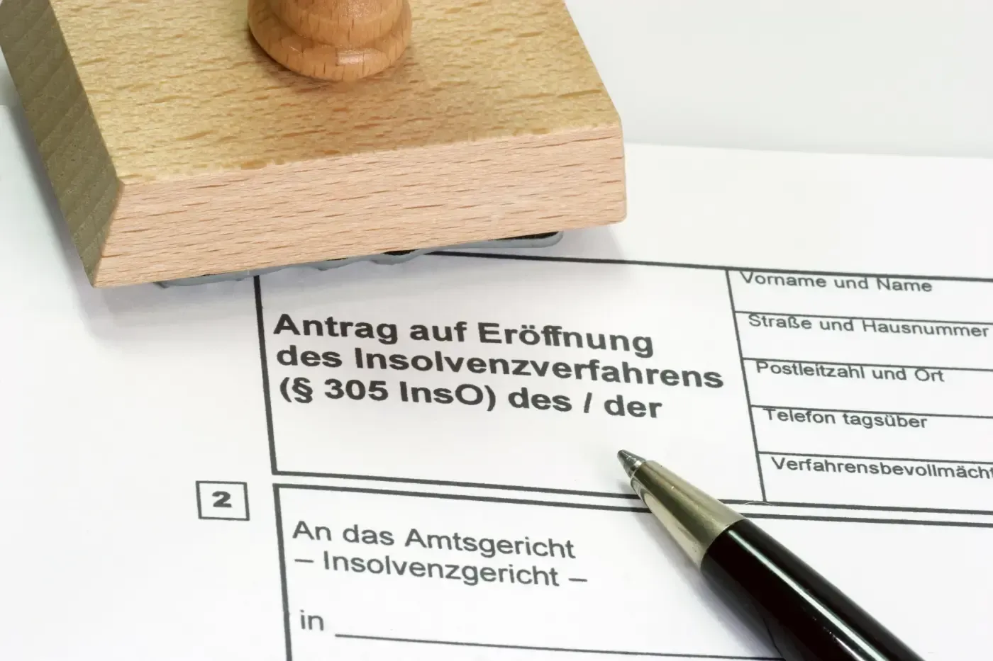 Nahaufnahme eines deutschen Insolvenzantragsformulars mit Stempel und Stift, bereit zum Ausfüllen.