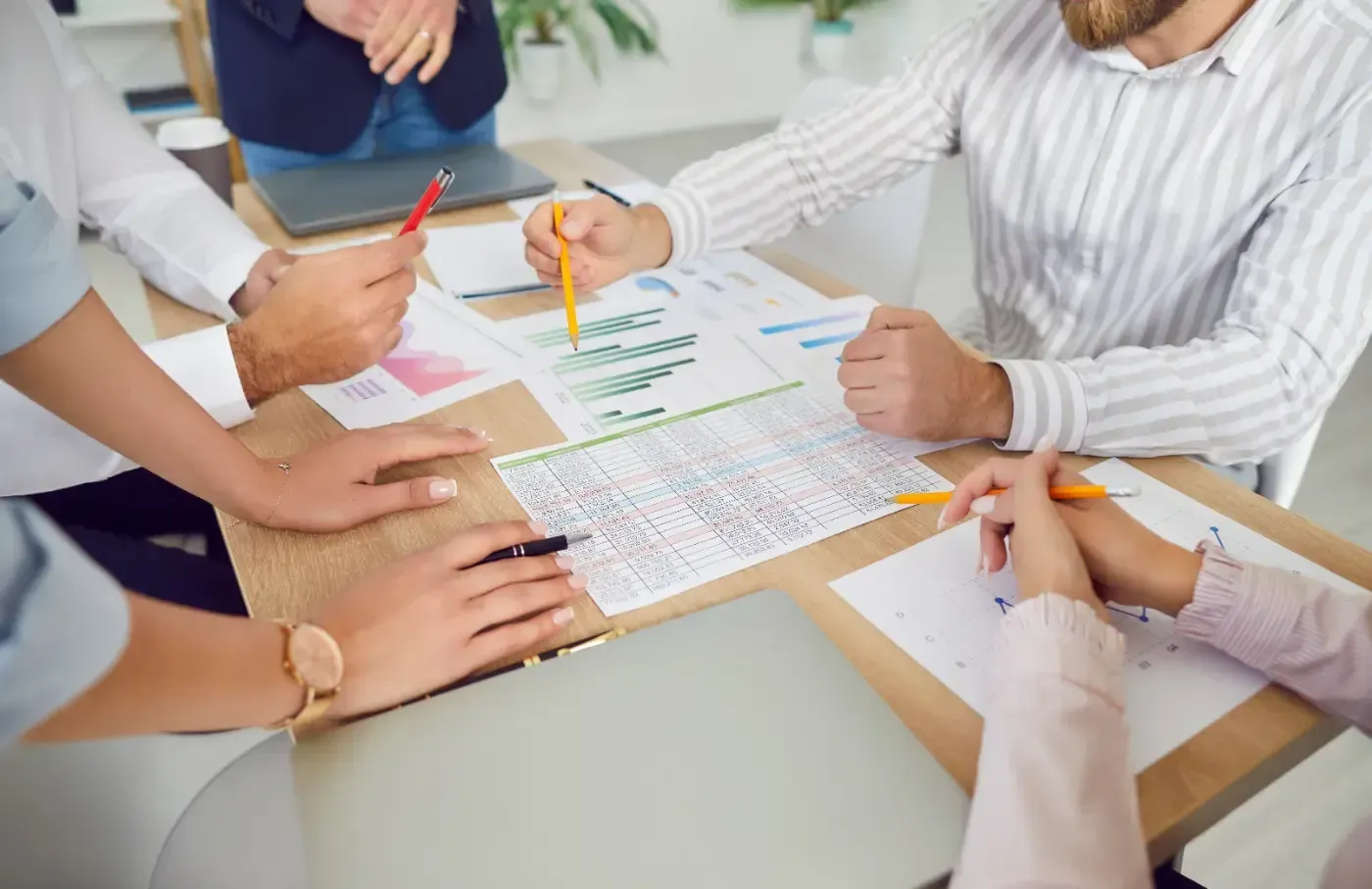 Menschen arbeiten gemeinsam an einem Tisch mit Papier, Diagrammen und Stiften.