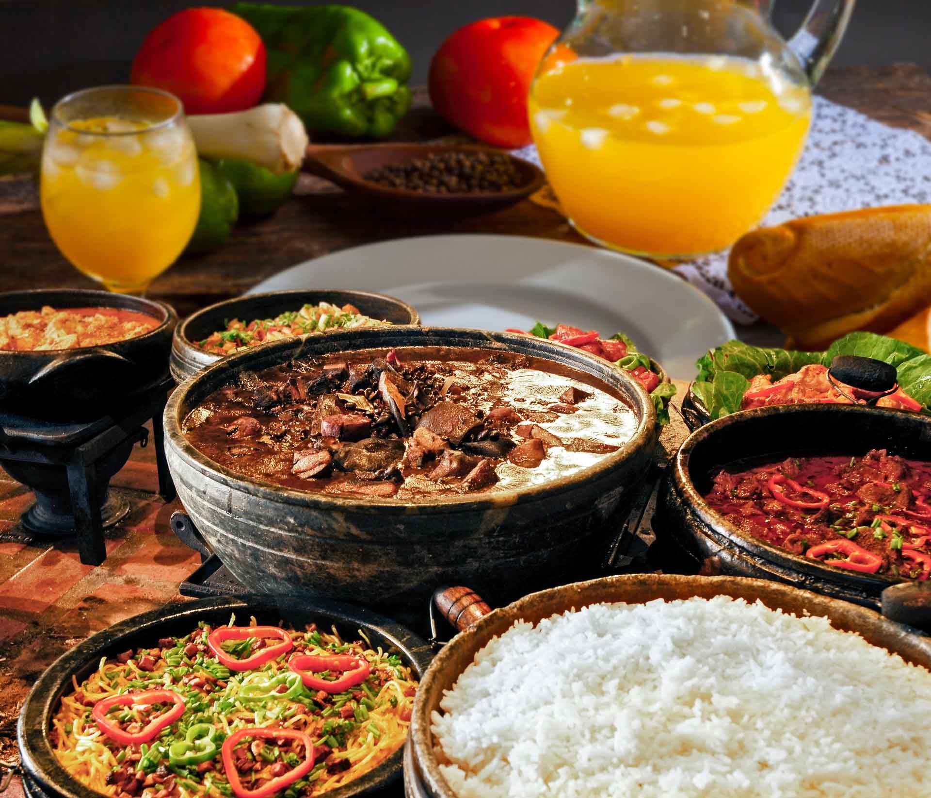Una mesa cubierta con cuencos de comida y una jarra de jugo de naranja.