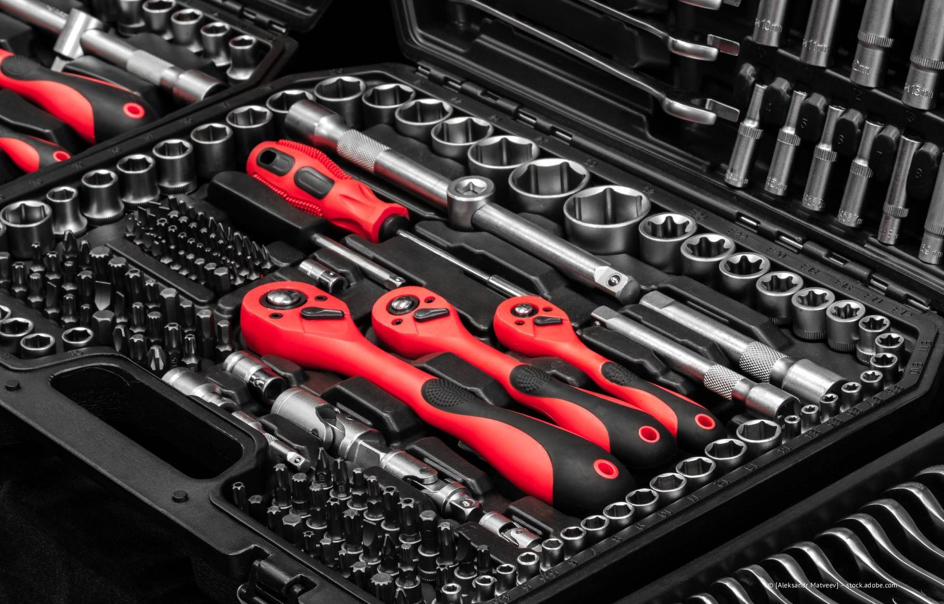 Offener Werkzeugkasten gefüllt mit einer Vielzahl roter und silberner Mechanikerwerkzeuge, darunter Ratschen, Steckschlüssel und Schraubendreher.