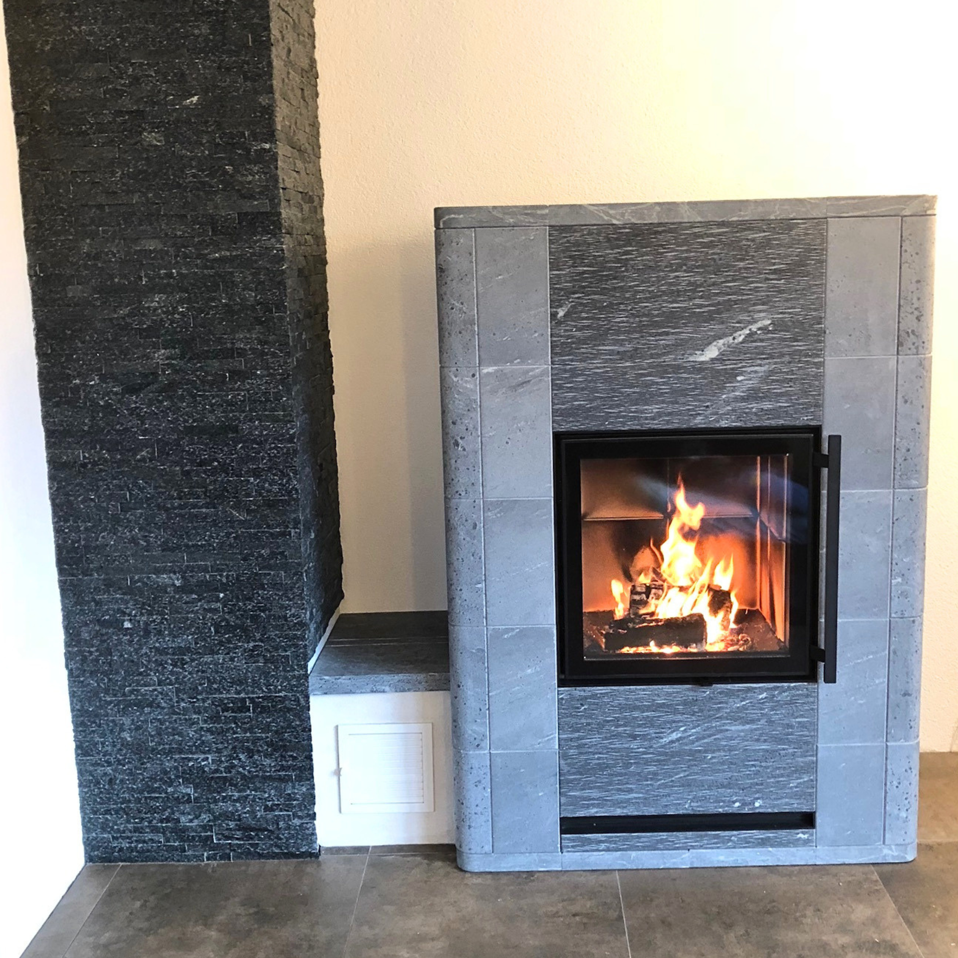 TULIKIVI-Specksteinöfen_SALVO mit kleiner Ofenbank links 