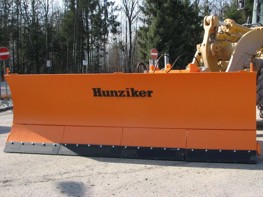 Orangefarbener Hunziker-Schneepflug, wahrscheinlich an einer Planierraupe befestigt, auf einer 