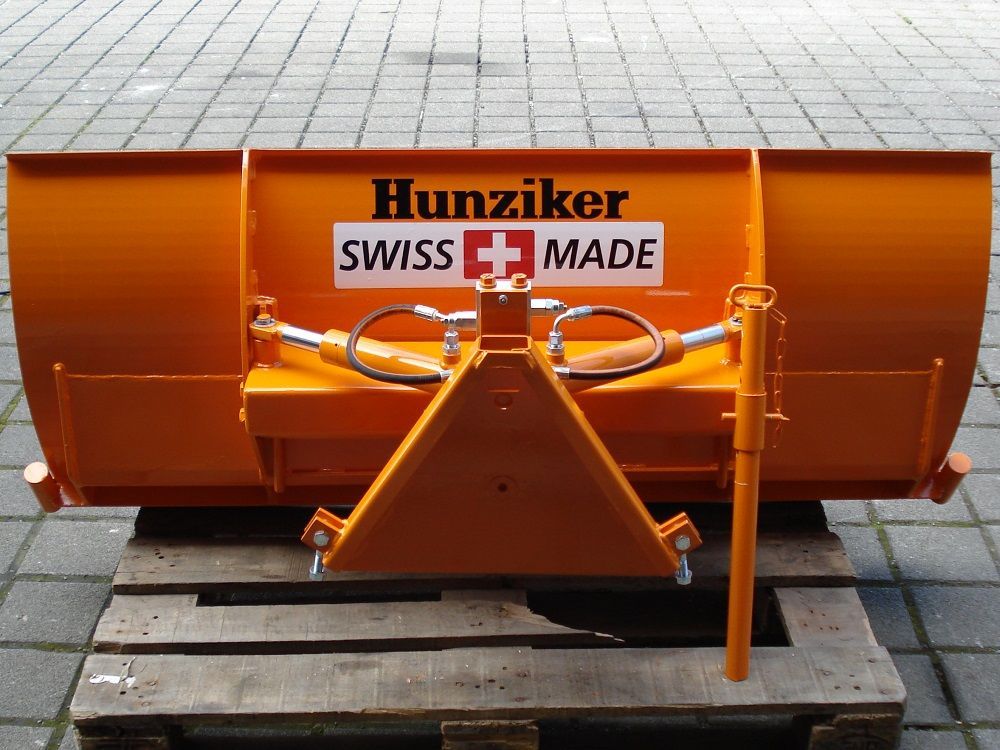 Oranger Schneepflug mit „Hunziker SWISS MADE“-Logo, einsatzbereit auf einer Holzpalette montiert.