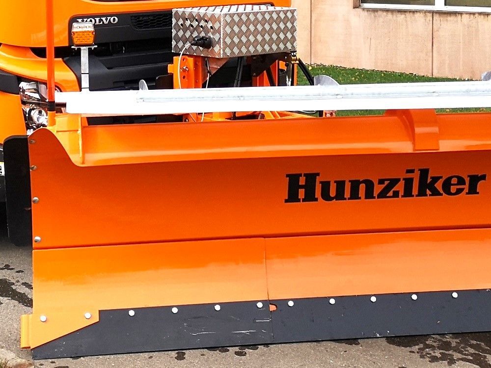 Orangefarbener Schneepflug mit dem Namen „Hunziker“ auf der Seite.