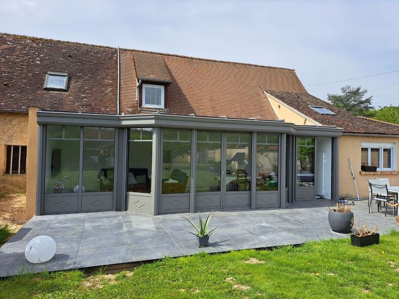 Terrasse de maison en dalle adjointe à une véranda