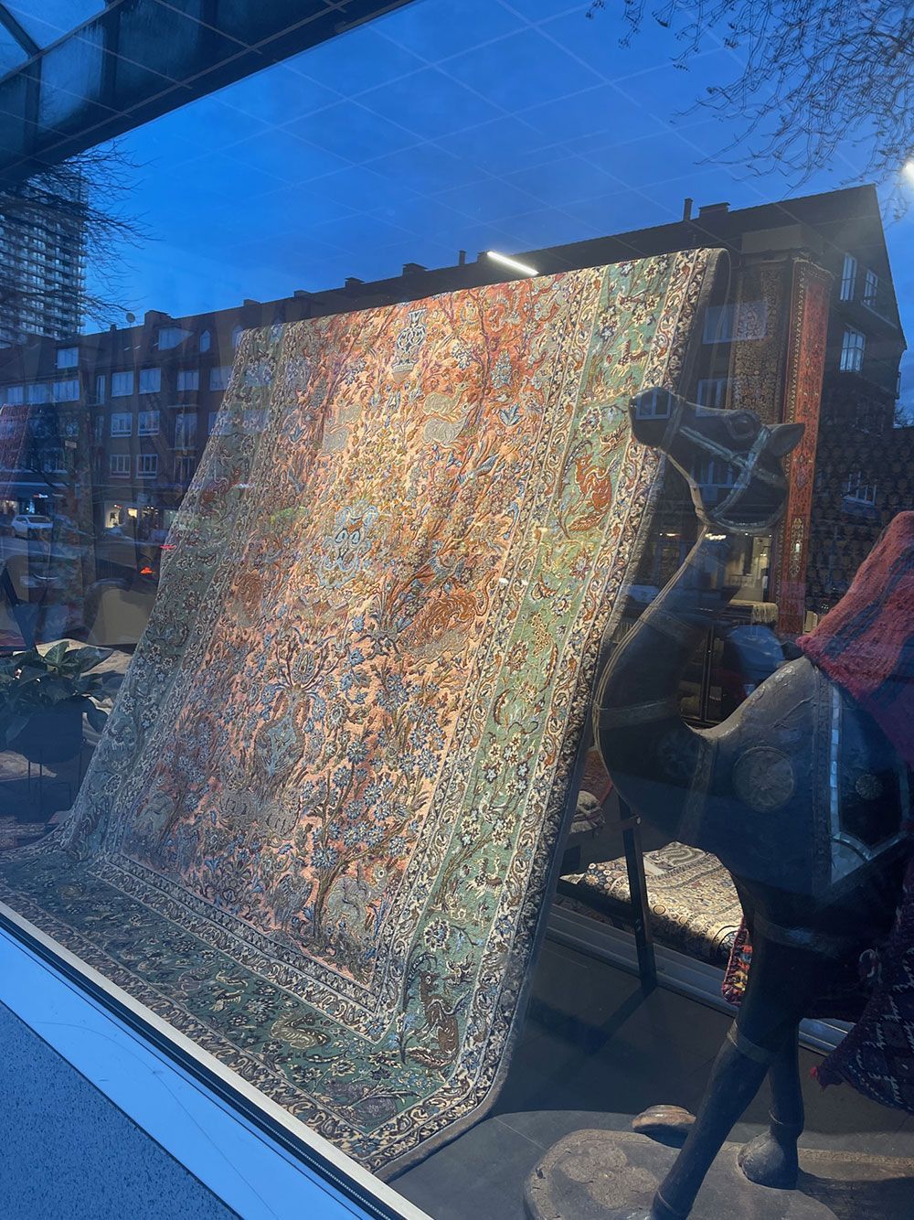 In einem Fenster hängt neben einer Hirschstatue ein großes Gemälde.