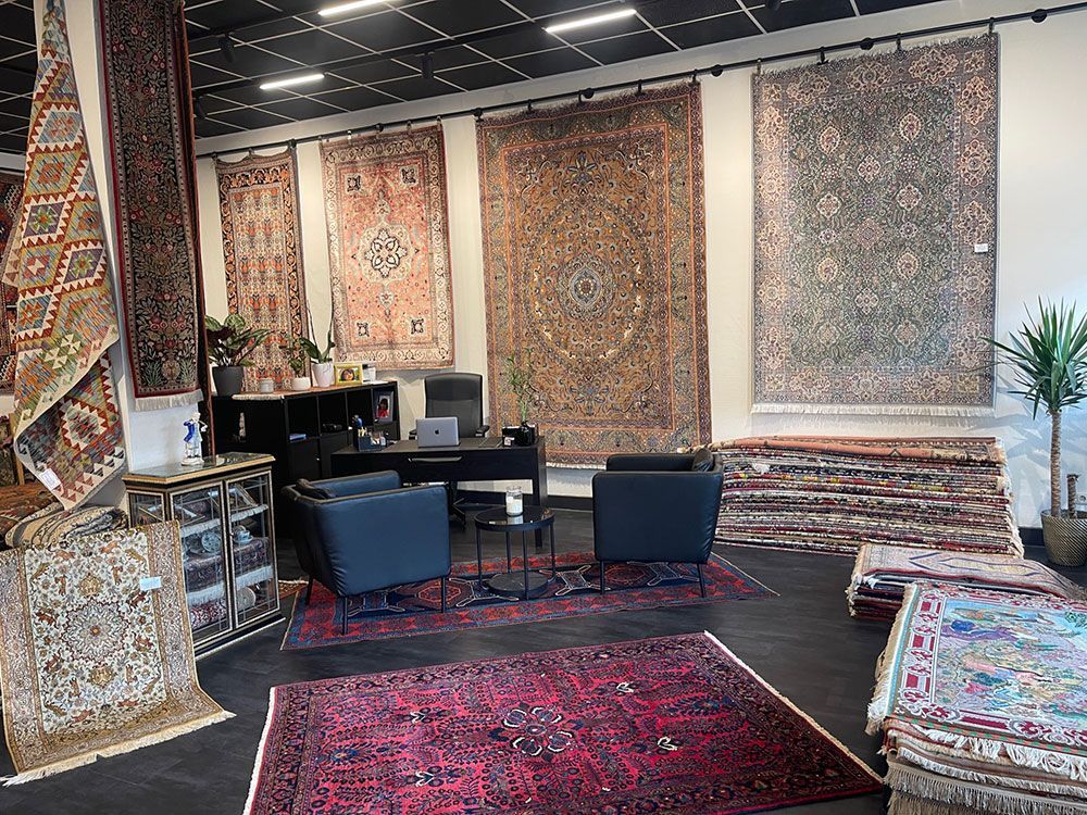 Ein Wohnzimmer mit vielen Teppichen und Stühlen.