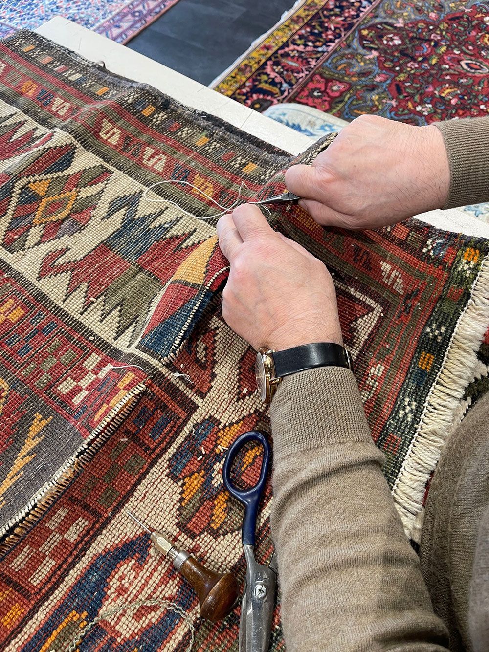 Eine Person schneidet einen Teppich mit einer Schere.