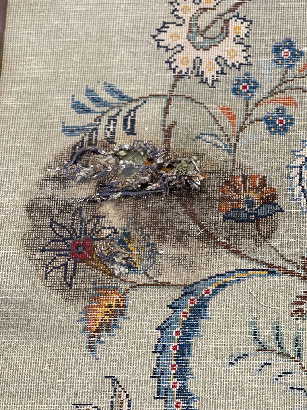 Eine Nahaufnahme eines mit Blumen bestickten Teppichs mit einem Vogel darauf.