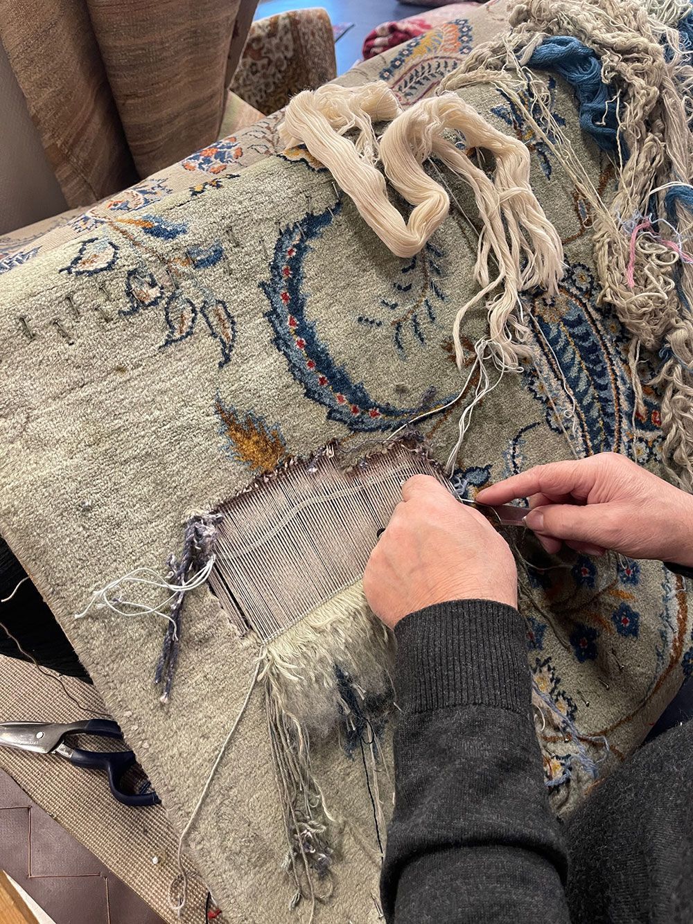 Eine Person bearbeitet einen Teppich mit einer Schere.