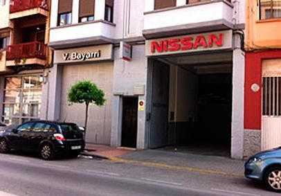 Un coche está aparcado delante de un edificio que dice Nissan.
