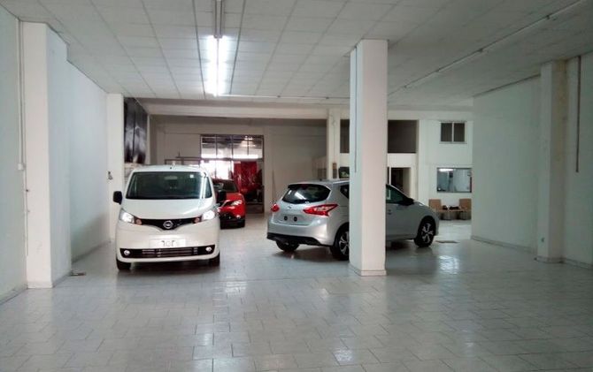 Una furgoneta blanca y un coche plateado están aparcados en un garaje.