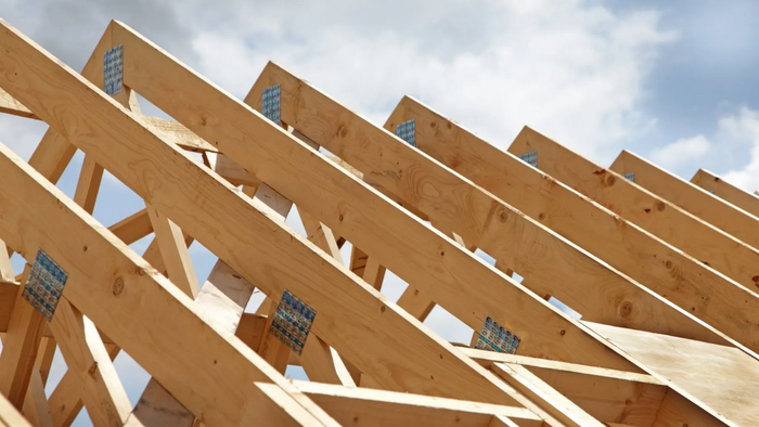Charpente de toit en bois en construction sous un ciel nuageux