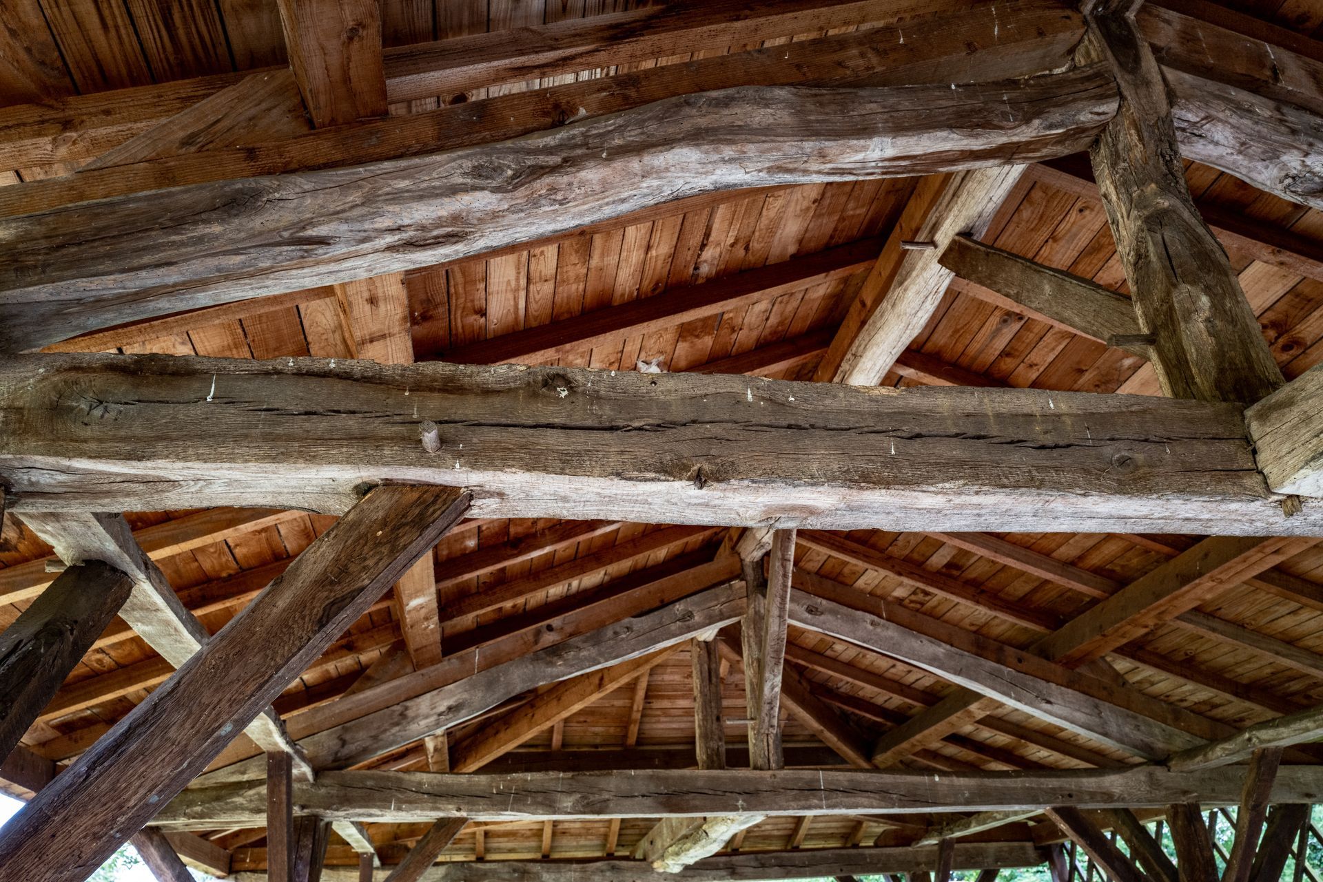 Poutres et chevrons en bois rustiques soutenant un intérieur de toit patiné