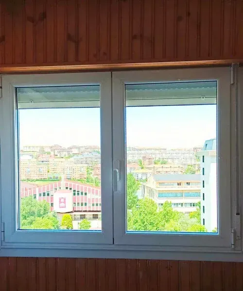 Ventana de dos paneles con vista a la ciudad. Paneles de madera rodean el marco.