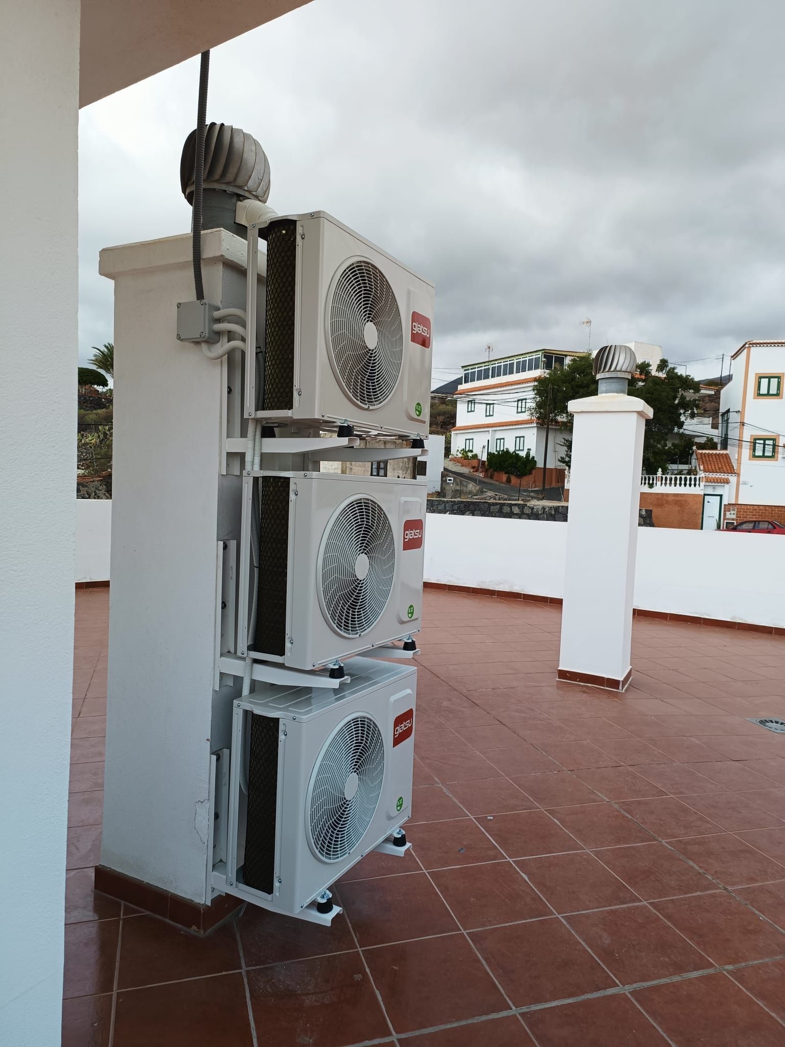 Tres aparatos de aire acondicionado están apilados uno encima del otro en un tejado.
