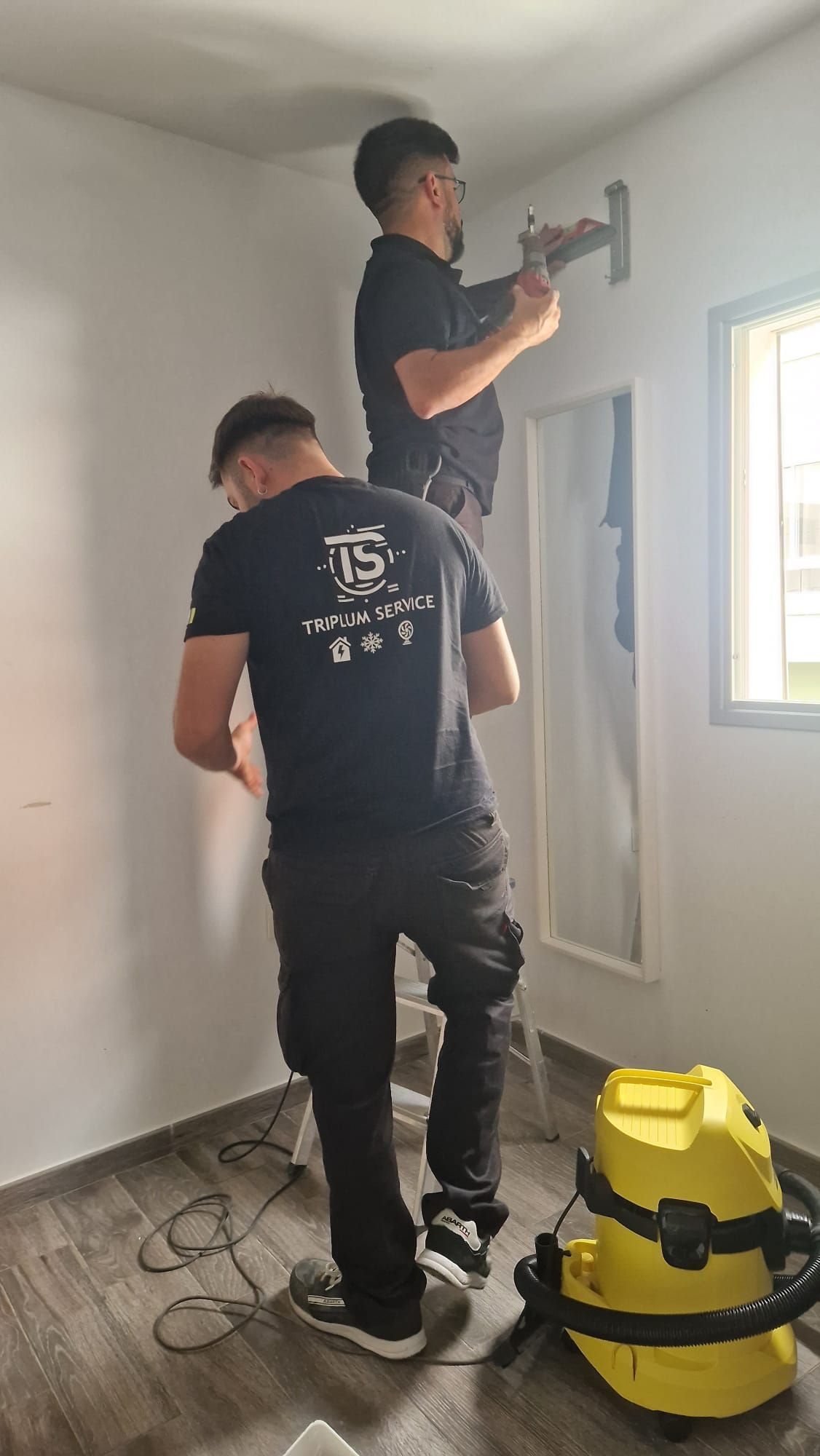Dos hombres están trabajando en una pared de una habitación.