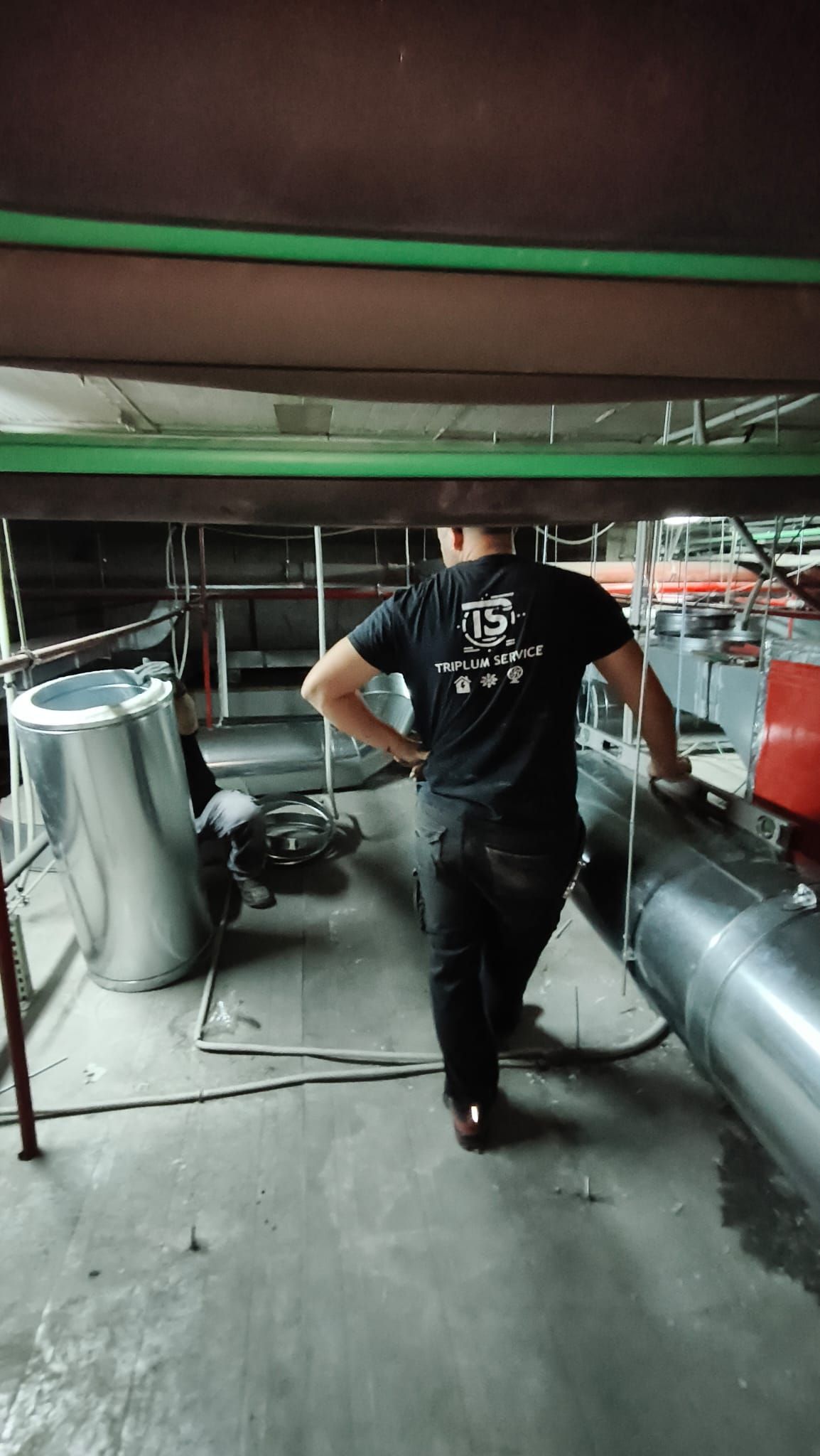 Un hombre está parado bajo un techo en una habitación con tuberías.