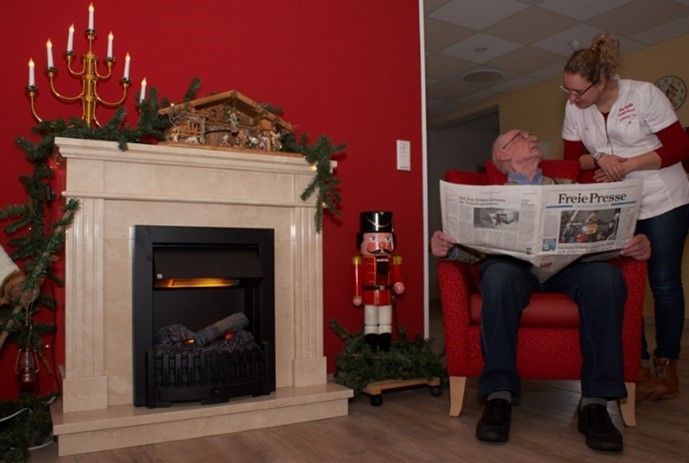 Eine Person sitzt auf eine Couch bei Margit's Pflegedienst und liest eine Zeitung