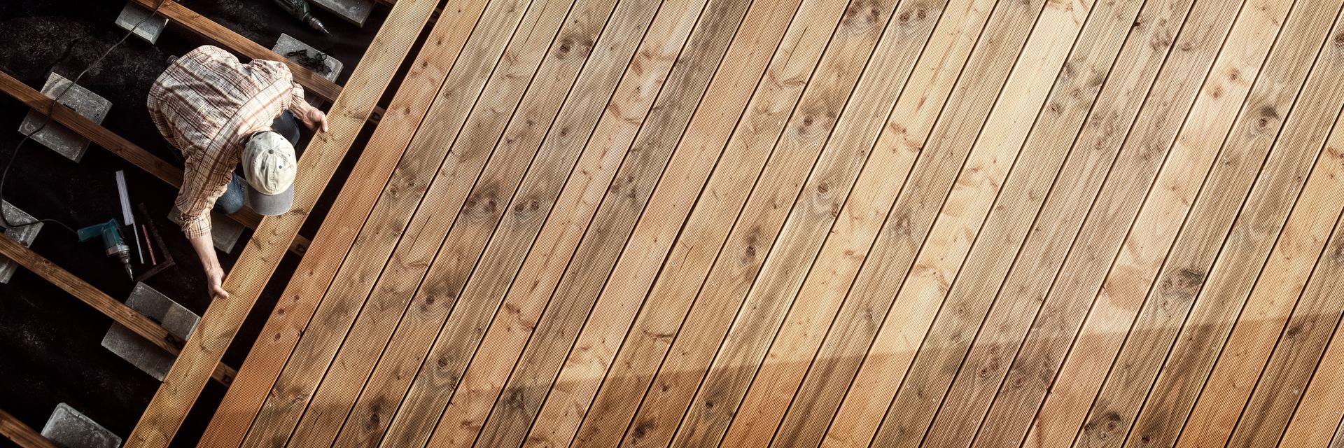 Vue aérienne d'une personne installant des planches de terrasse en bois sur une structure.