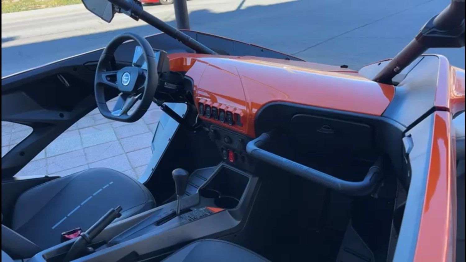 Primer plano de un todoterreno plateado. Asiento y manillar negros con retrovisores. Afuera, sobre un camino de ladrillos.