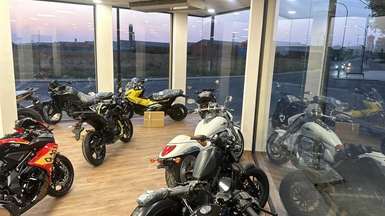 Motocicletas estacionadas en una acera frente a una tienda con un gran escaparate.