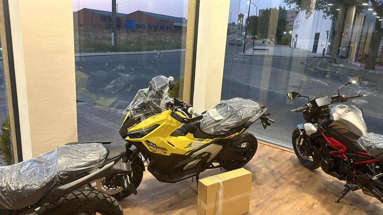 Cascos de motocicleta en exhibición en una tienda, varios colores y diseños, junto a vehículos todo terreno.