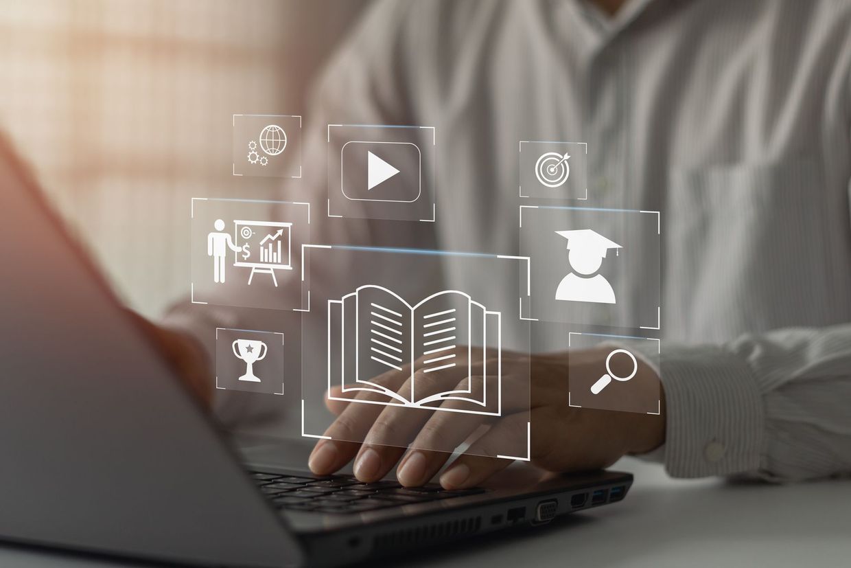 Personne utilisant un ordinateur portable avec des icônes superposées représentant l'éducation, notamment un livre, un bouton de lecture vidéo et une casquette de remise de diplôme.