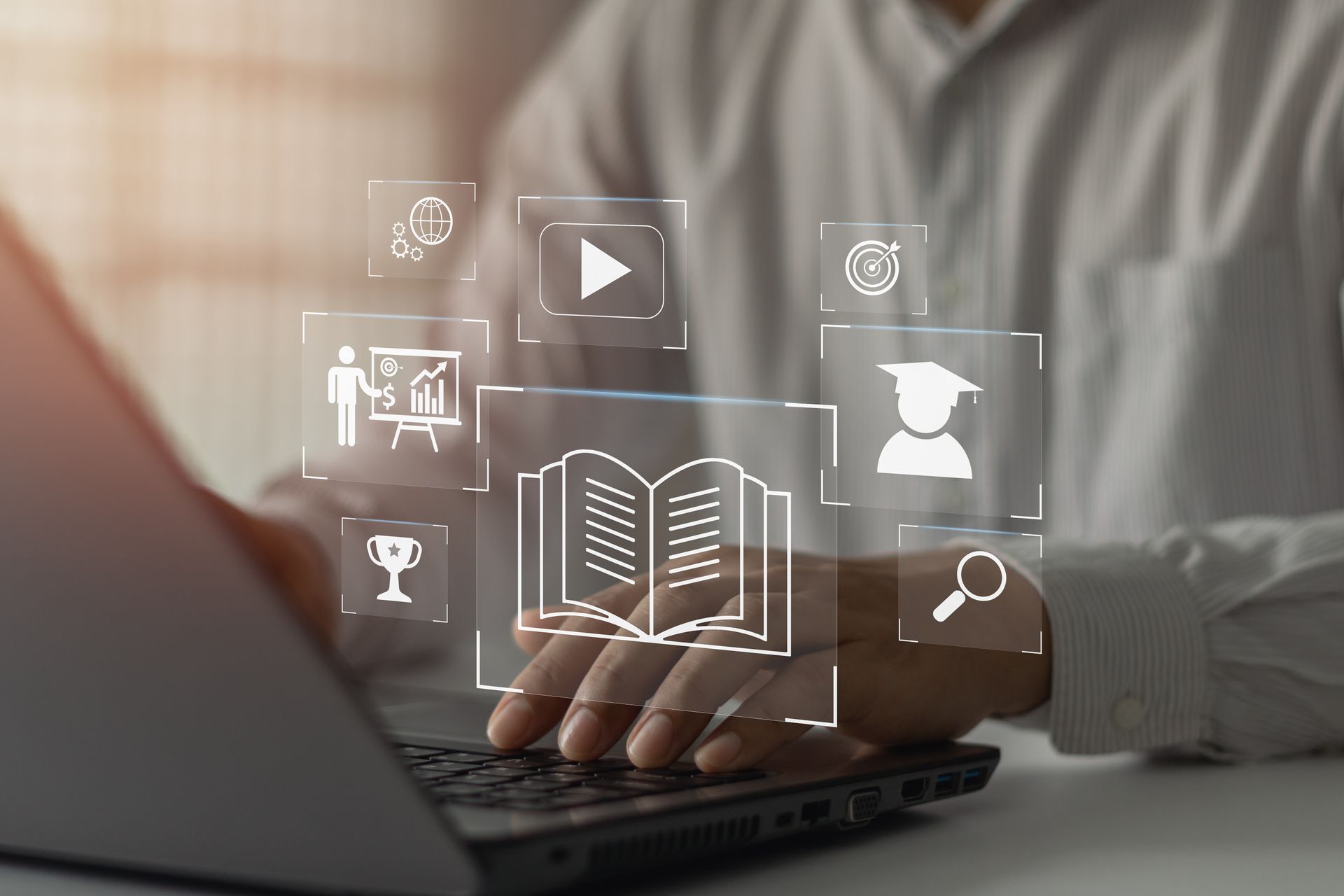 Personne utilisant un ordinateur portable avec des icônes superposées représentant l'éducation, notamment un livre, un bouton de lecture vidéo et une casquette de remise de diplôme.