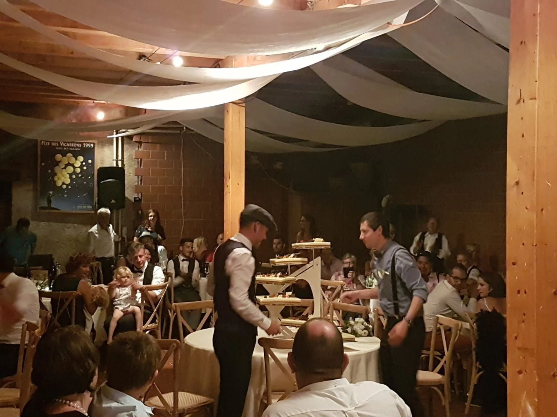 Deux hommes maintiennent en équilibre une structure en bois sur des assiettes lors d'un événement.