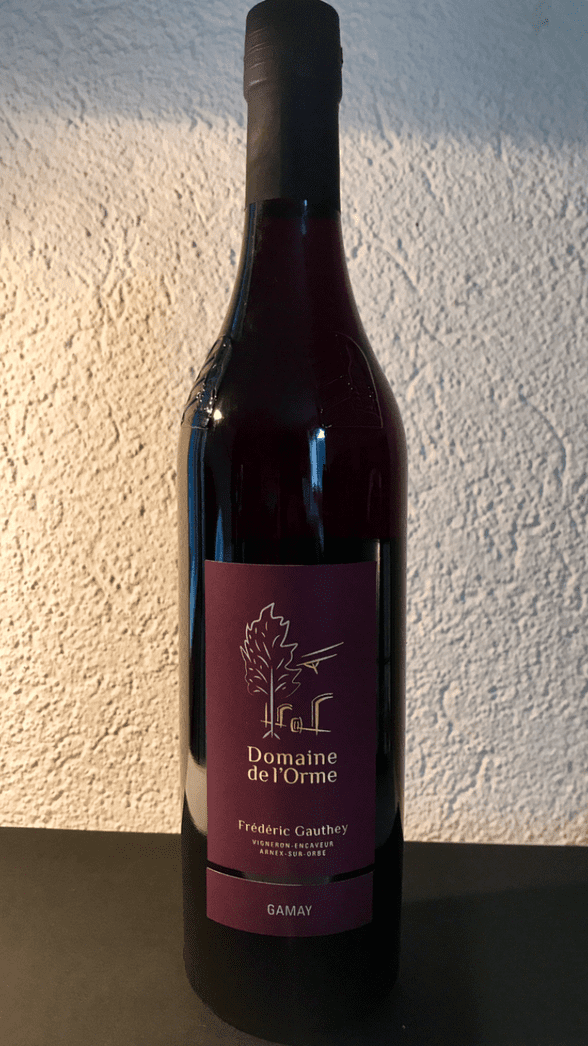 Bouteille de vin, liquide rouge foncé, étiquette noire avec inscription dorée.